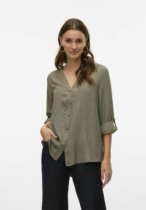 Chemise olive verte à boutons, avec un col en V, des manches longues et des poignets retroussés ; fabriquée en tissu texturé avec une coupe décontractée.