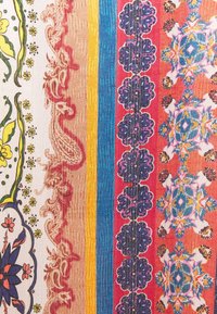 Tissu multicolore avec des rayures verticales présentant des motifs floraux, paisley et géométriques dans des tons de jaune, bleu, rouge, violet et beige.