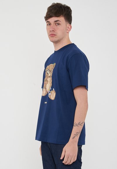 Maglietta di cotone blu navy con una grafica di un orso cartone sul davanti, con maniche corte e colletto a girocollo.