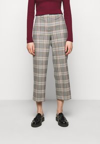 Grå rutiga beskurna byxor med hög midja, som har en blandning av vita, röda och gula linjer. Materialet verkar texturerat. Svarta skor ingår.