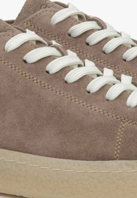 Zamszowe sneakersy w jasnobrązowym kolorze z białymi sznurówkami. Posiadają teksturowaną cholewkę oraz grubą, lekko przezroczystą gumową podeszwę.