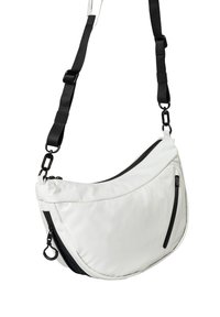Weiße Stoff-Crossbody-Tasche mit schwarzen Reißverschlussakzenten, geschwungener Form, verstellbarem schwarzen Gurt und zusätzlicher Reißverschlusstasche an der Seite.