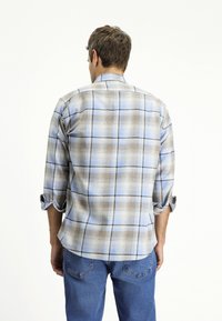 Heren geruit overhemd met een blauw, beige en bruin ruitpatroon, knoopmanchetten en een afgeronde zoom. Gemaakt van lichtgewicht stof.