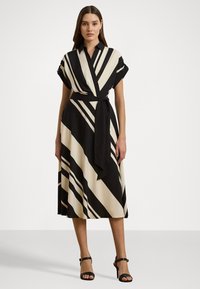 Melnas un krēmkrāsas svītrainā apģērba kleita ar īsām piedurknēm, ar jostu viduklī un plūstošu svārku. Gluda auduma ar strukturētu apkakli.