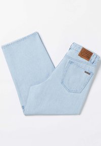 Jean en denim bleu clair avec une coupe droite, doté d'une patch en cuir marron à la taille et d'une poche arrière. Texture de tissu lisse.