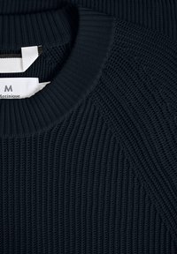 Navy ribbed sweater with a round neck, featuring textured knit patterns and a label showing the brand name "Matinique."