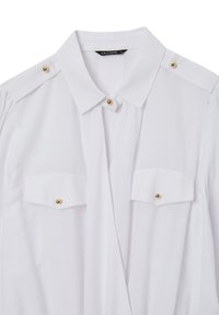 Camicia bianca con colletto, realizzata in tessuto liscio, con dettagli in bottoni d'oro sulle spalle e due tasche sul petto con chiusura a bottone.