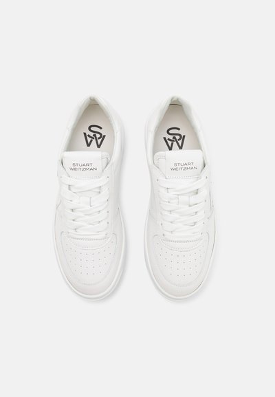 Sneakers bianchi in pelle con punte perforate, lacci piatti e linguetta con marchio. Texture liscia e elementi di design minimalisti in tutto.