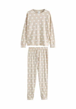 Beige pyjamaset med långärmad topp och byxor. Tyget har ett upprepat mönster av vita pumpor. Elastisk midja på byxorna.
