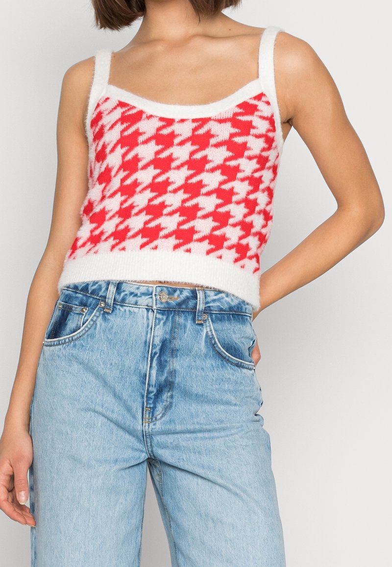 Červený a bílý pletený crop top s motivem psa zubatého se širokými ramínky a chlupatou texturou, kombinovaný s vysokým pasem světlých modrých džín.