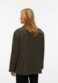 Prevelik blazer iz volnene mešanice v temno rjavi barvi z teksturirano obdelavo, z zarezanim ovratnikom in rokavi z ravnim krojem ter z zadnjo ventilsko podrobnostjo.