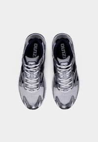 Harmaat ja mustat verkkokankaiset urheilukengät, joissa pyöristetty kärki, teksturoitu pinta ja kontrastiväriset yksityiskohdat sivuilla ja nauhoissa.