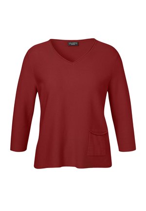 Haut rouge à manches trois quarts avec un décolleté en V. Il présente une poche à l'avant et un tissu texturé, offrant une coupe décontractée.