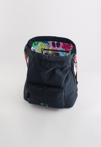Geantă din material textil negru, cu un interior colorat și cu model și curea. Are o buzunar frontal și un exterior moale, texturat.