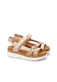 Sandali beige con suola in sughero imbottita. Presentano dettagli in oro metallizzato e più cinghie che attraversano il piede. Cinturino alla caviglia regolabile per una vestibilità perfetta.