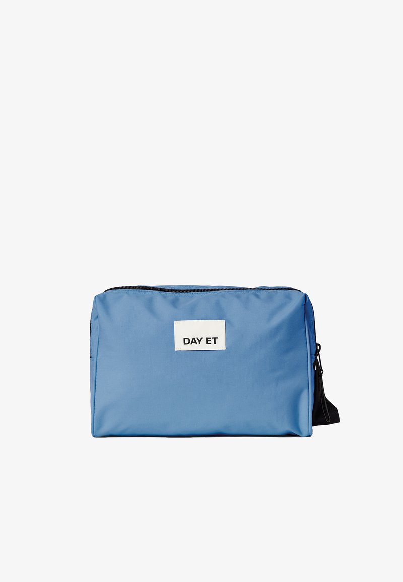 Sac en nylon bleu de forme rectangulaire, avec une fermeture éclair sur le dessus, une sangle noire et une étiquette blanche affichant "DAY ET". Texture lisse.