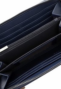 Interno di un portafoglio in pelle blu navy con più scomparti per carte, un compartimento con zip e una texture liscia; dettagli cuciti visibili.