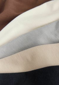 Fabric swatches in brown, cream, gray, beige, and black. Soft, textured materials arranged in overlapping layers.