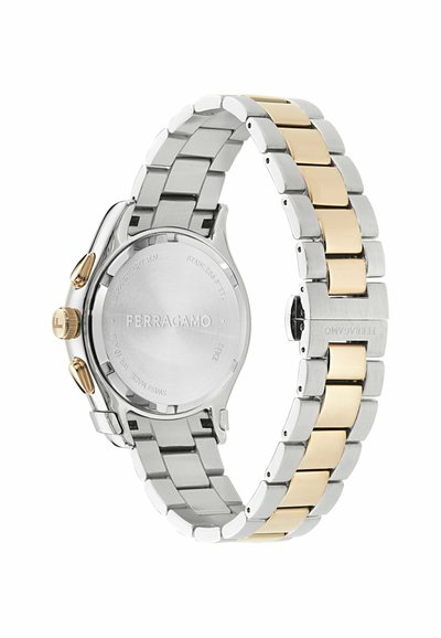 Reloj de pulsera de metal plateado y dorado con una pulsera de eslabones bicolor, con la marca Ferragamo visible en el cierre y en la parte trasera de la caja.