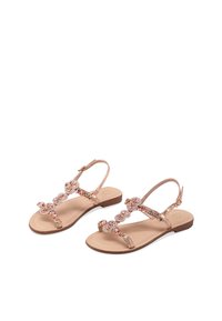 Sandal con suola piatta, caratterizzata da una base in pelle color tan e una fascia decorata con gemme finte color oro rosa disposte a forma di roselline.