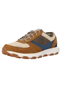 Baskets marron et beige avec accent bleu, en matériau suédé/cuir, semelle en caoutchouc avec traction et lacets texturés. Présente un logo sur le côté.