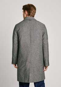 Abrigo de mezcla de lana en un patrón de espiga gris. Presenta un corte entallado, solapa con pico y una abertura en la parte trasera. Diseño de longitud media.