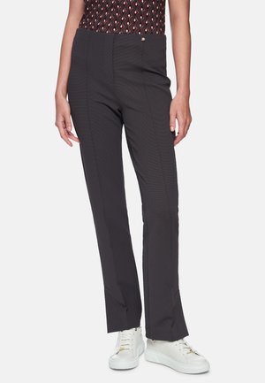 Schwarze gemusterte Hose mit enger Passform, glatter Textur und maßgeschneidertem Schnitt, kombiniert mit weißen Sneakers.