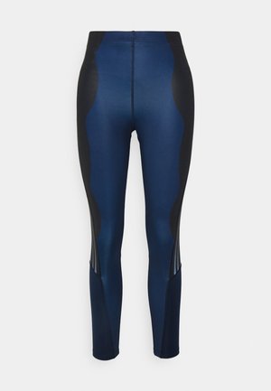 Námořnicky modré legíny s černými bočními panely, které mají hladkou texturu a kontrastní švy, navrženy pro aktivní nošení.