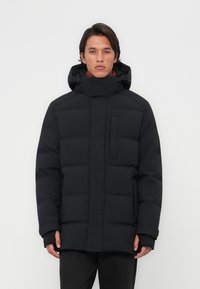 Chaqueta acolchada negra aislante con cuello alto, bolsillo delantero y capucha. Textura suave, patrón acolchado y puños doblados.
