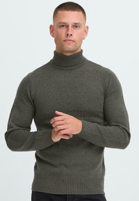 Dunkelgrüner Rollkragenpullover mit geripptem Textur, langen Ärmeln und tailliertem Design. Der Kragen ist dezent strukturiert für zusätzliche Details.