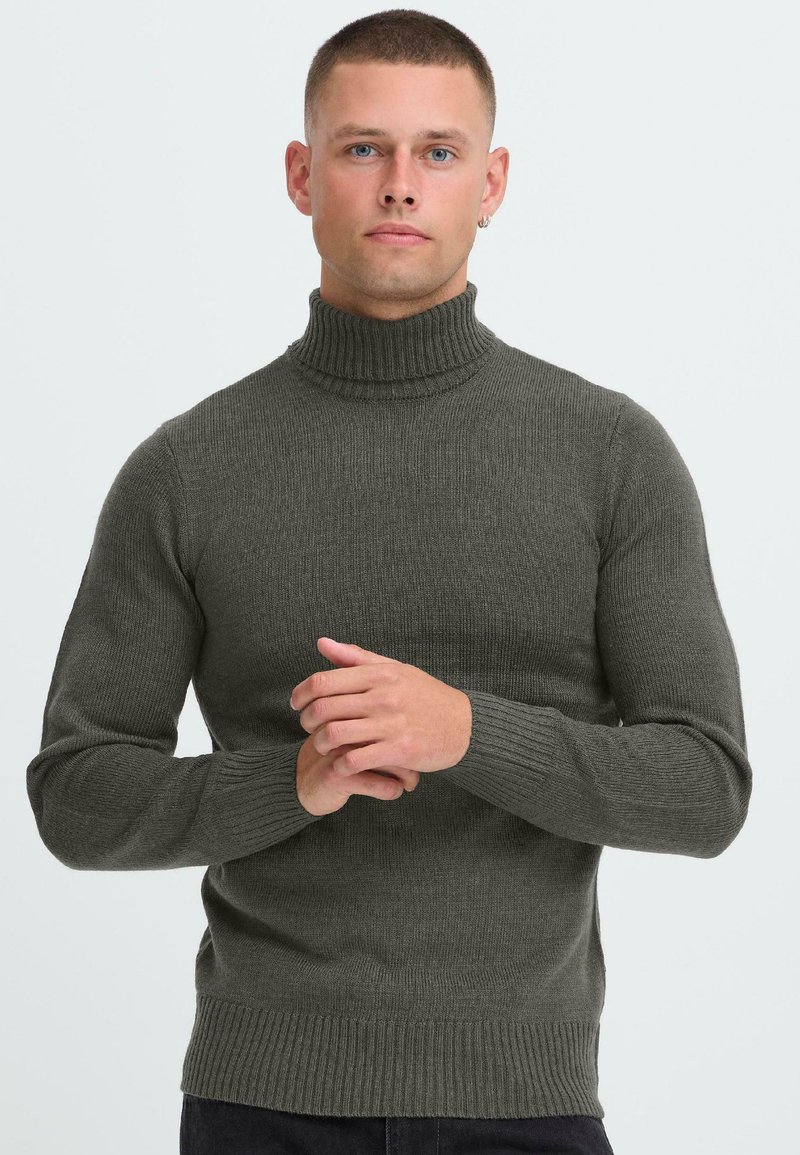 Dunkelgrüner Rollkragenpullover mit geripptem Textur, langen Ärmeln und tailliertem Design. Der Kragen ist dezent strukturiert für zusätzliche Details.