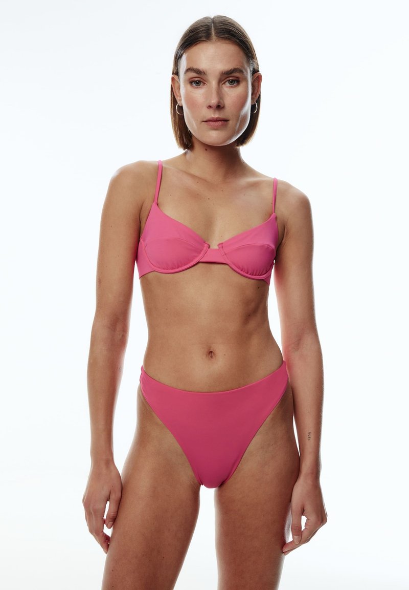 Rosa Bikini-Set mit gepolstertem Bralette und dünnen Trägern sowie hochgeschnittenen Unterteilen. Glatte Textur, nahtloses Design und lebendige Farbe.