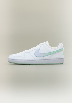 Baskets basses blanches avec le swoosh Nike bleu clair et vert, lacets blancs et semelle à accents verts sur un fond neutre.