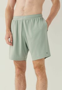 Jasnozielone spodenki sportowe wykonane z gładkiego, oddychającego materiału, z elastycznym pasem i bocznymi kieszeniami. Zawierają subtelny teksturowany wzór.