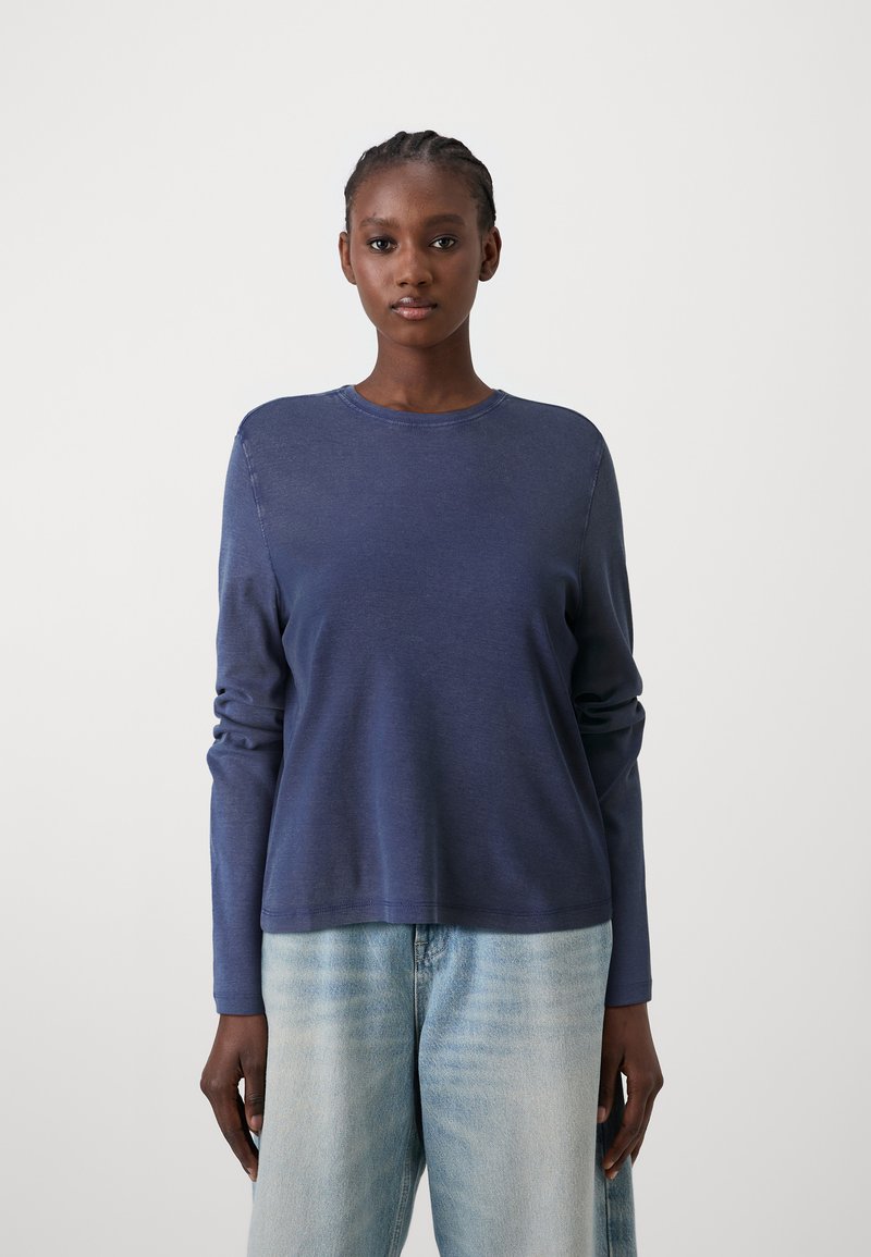 Dunkelblauer Langarm-Crewneck-Pullover mit glatter Textur und geripptem Kragen. Kombiniert mit hellblauen, locker sitzenden Jeans.