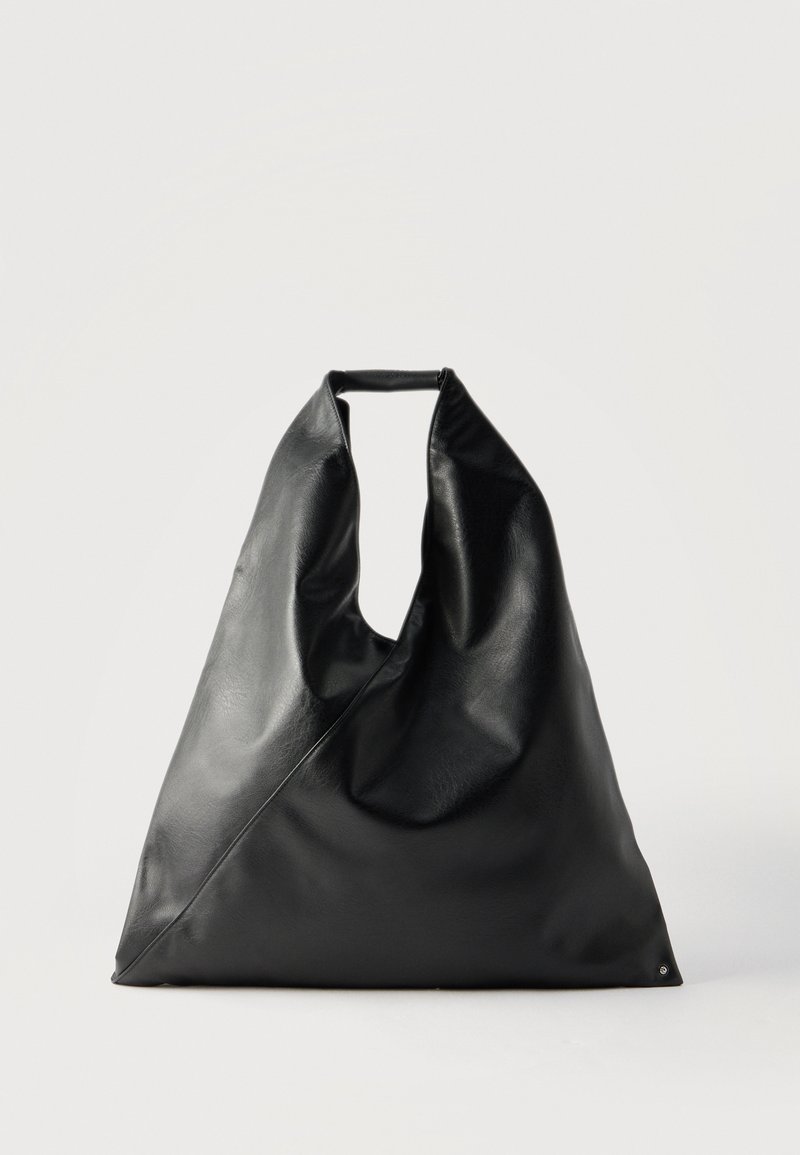 Sac fourre-tout triangulaire en cuir noir avec une anse souple et des détails de couture minimalistes sur un fond clair uni.