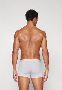 Boxer da uomo grigi realizzati in tessuto morbido, design aderente, con una consistenza liscia e una vita semplice. Visti da dietro.