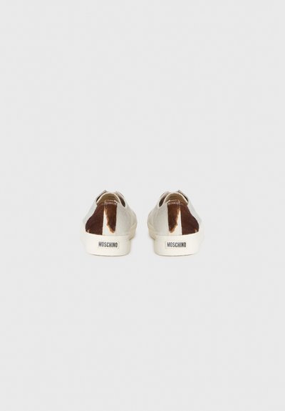 Sneakers med en beige canvas kropp och bruna och vita cowhide-mönster-accenter, logotyp på hälen och rund tådesign.