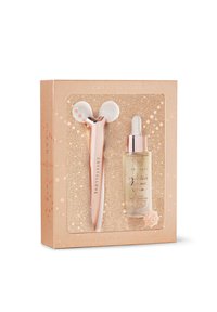 Gesichtsmassager aus klarem Quarz mit einem roségoldenen Griff, kombiniert mit einem gold-tönenden Schimmer-Serum in einer glitzernden roségoldenen Schachtel.