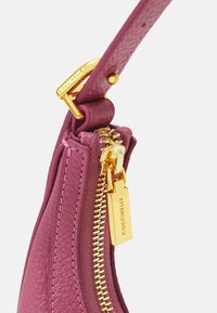 Różowa skórzana torebka o teksturowanym wykończeniu, z złotym metalowym zamkiem błyskawicznym i uchwytem, uzupełniona o metkę marki.