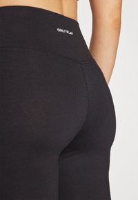Svarte høyt liv leggings laget av elastisk stoff med en glatt tekstur. Har hvit "ONLY PLAY" logo på midjebåndet.