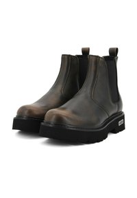 Brązowe skórzane botki Chelsea z elastycznymi bocznymi panelami, masywnymi czarnymi podeszwami i uchwytami do łatwego zakładania. Teksturowane wykończenie dodaje głębi.