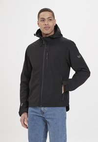 Giacca softshell nera con zip frontale, cappuccio regolabile e tasche laterali. Caratterizzata da una finitura testurizzata e da un logo sulla manica.