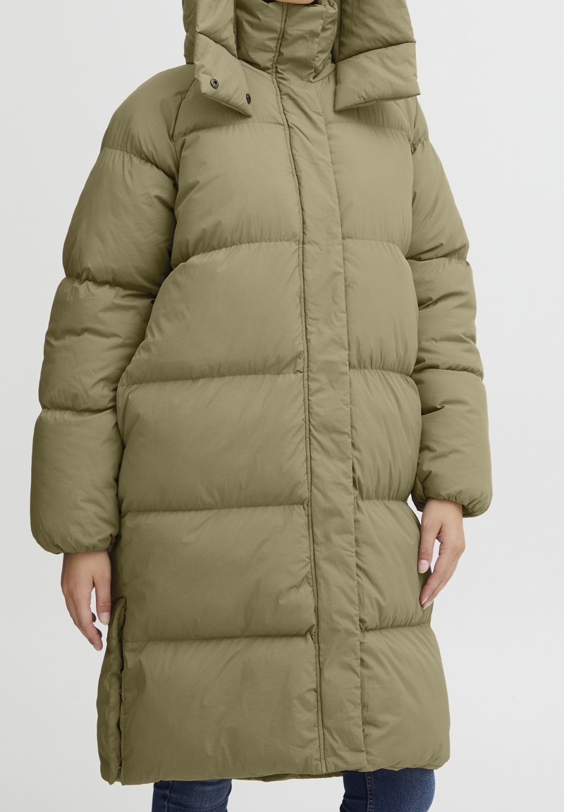 Olivenfarvet pufferjakke med quiltet design, høj krave og lynlåslommer. Materialet virker let og vandafvisende.