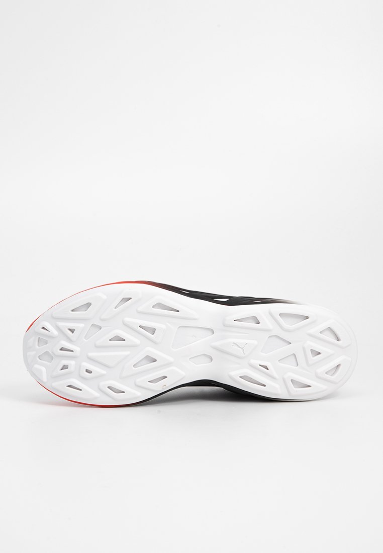 Semelle de chaussure de sport noire avec une semelle intermédiaire blanche texturée et des accents rouges. Dotée d'un motif géométrique pour l'adhérence et la traction.