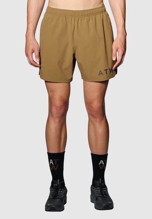 Braune Shorts mit einem elastischen Bund und Seitentaschen. Mit "ATW" in Schwarz bedruckt. Tragen Sie sie mit schwarzen Socken und Sportschuhen.