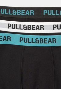 Schwarze und graue Baumwoll-Boxershorts mit kontrastierenden elastischen Taillenbändern. Die Taillenbänder tragen das "PULL&BEAR"-Logo in schwarzem und türkisfarbenem Text.