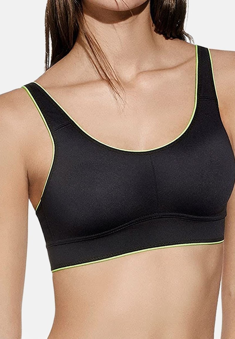 Sujeción deportiva negra con una banda ancha y una textura suave, con detalles en verde brillante a lo largo del escote y las correas.