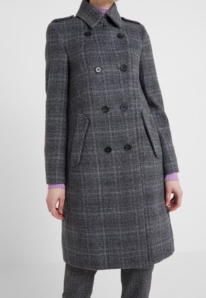 Manteau gris à carreaux à double boutonnage avec boutons noirs porté sur un pantalon assorti à carreaux et un pull côtelé lavande.
