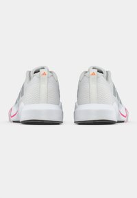 Scarpe sportive grigie con tomaia in mesh testurizzato, suole bianche, dettagli rosa e logo sul tallone, caratterizzate da un colletto arrotondato e imbottito.